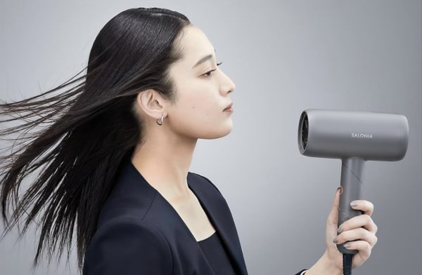 低温ドライヤーで髪を乾かす女性