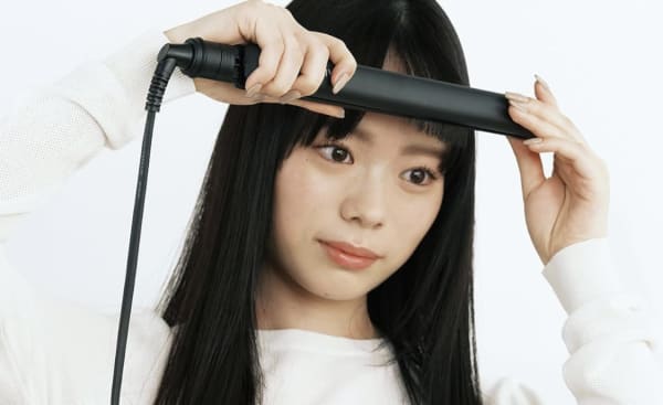 前髪をヘアアイロンでセットする女性