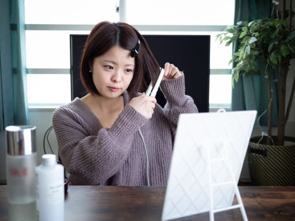 ストレートアイロンでスタイリングをするショートへの女性