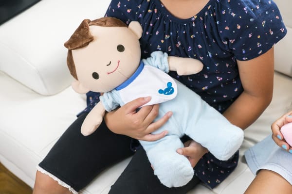 赤ちゃんロボットを抱っこする子ども