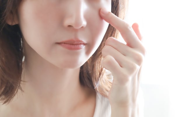 目の下を押さえる女性