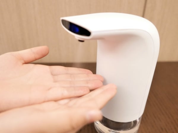自動アルコールディスペンサーを使う様子