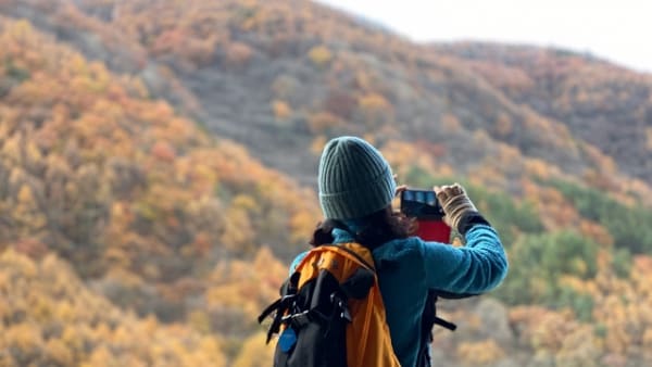 スマホで遠くの山を撮影する女性