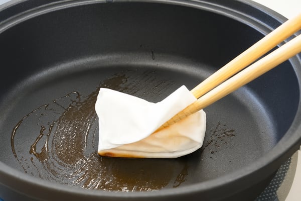 鍋の汚れを拭き取る様子