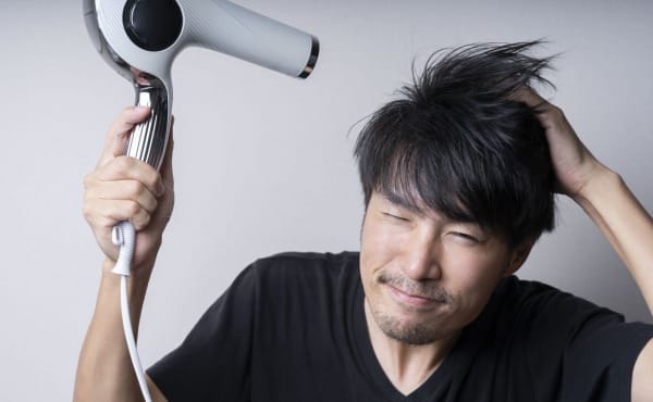 ドライヤーで髪を乾かす男性